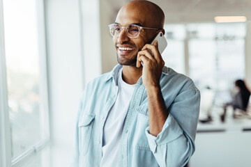 Poster - Young business man talking on a mobile phone in his workplace
