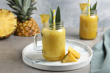 Tasty pineapple smoothie and sliced fruit on light grey table