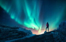 Northern Lights And Young Woman On Mountain Peak At Night. Auror