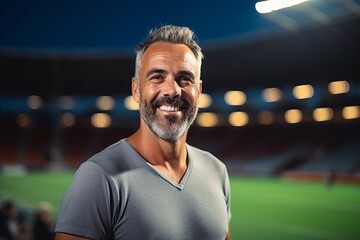 Portrait of smiling sportsman standing against view of football stadium at night