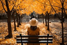 Woman Sitting At Autumn Park Bench