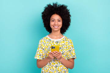 Sticker - Photo portrait of young optimistic smiling happy girl teenager wear print t shirt hold smartphone isolated on aquamarine color background