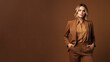 © Roxy jr. - A young blond woman in brown clothing stands against a solid brown background. Studio. Isolated brown background. Generative AI.