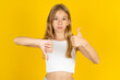 Young handsome man standing over yellow studio background showing thumbs up and thumbs down, difficult choose concept