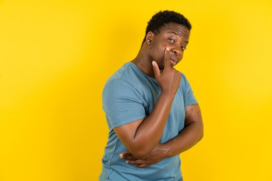 young handsome man standing over yellow studio background pointing to the eye watching you gesture, 