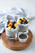 Vegetarian chia pudding with yogurt and fruits in jar on wooden serving board.