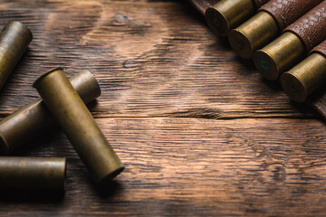 Old cartridge belt with empty brass sleeves on wooden table background. Hunting concept background with copy space.