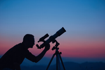 Wall Mural - astronomer looking at the night sky with a telescope.