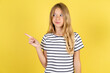 © Jihan - Beautiful caucasian kid girl wearing striped  T-shirt points at copy space and advertises something, advices best price.