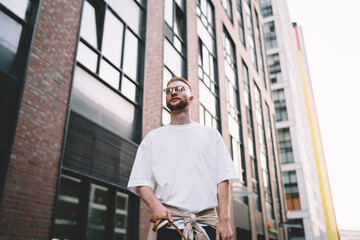 Serious man in eyeglasses standing near modern building