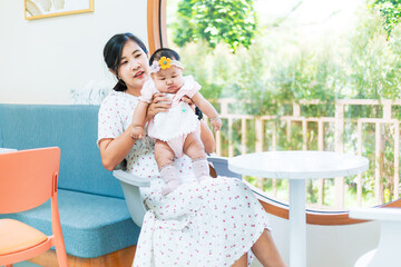 Asian woman holding a baby,Asian mother holding her sleeping baby looking at her and smiling while standing in the room