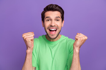 Sticker - Photo of impressed astonished man with stubble dressed green t-shirt raising fists win betting isolated on purple color background