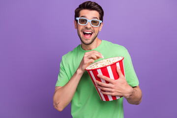 Sticker - Photo of impressed optimistic man with stubble dressed green t-shirt 3d glasses eat popcorn at cinema isolated on purple color background