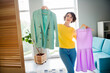 © deagreez - Portrait of dreamy lovely cute girl holding new collection clothes choosing look preparing going date indoors flat room