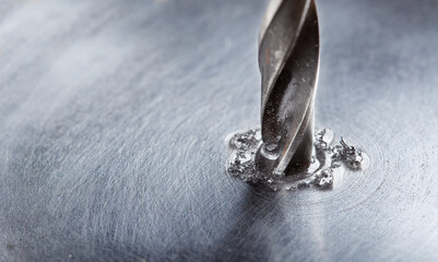 Wall Mural - metal drill bit with lubrication oil liquid make holes in steel billet on industrial drilling machine. Metal work industry