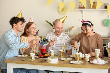 Canvas Print - Young woman cutting Birthday cake at party with her friends