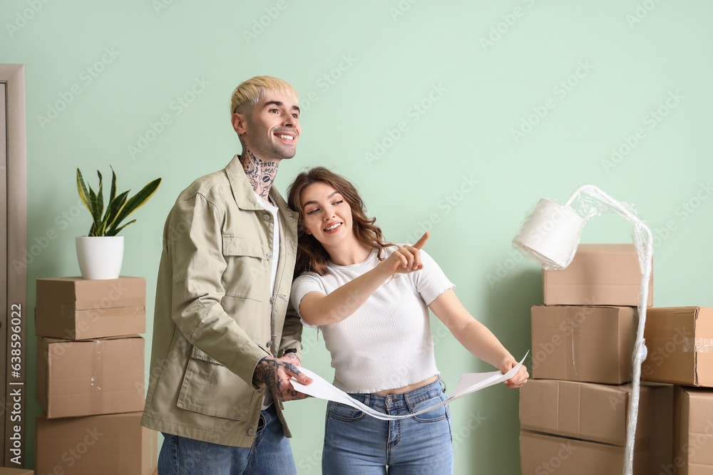 Young couple with house plan in room on moving day