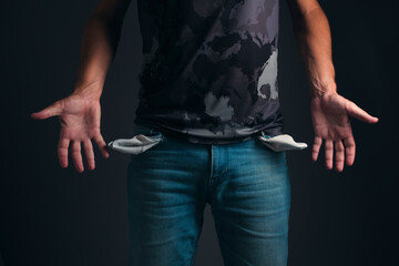 Man in T shirt and jeans with turned out, empty pockets.Concept of bankruptcy and poverty.