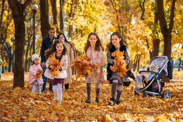 Wall Mural - portrait of big family in autumn city park, children running with armful of leaves, happy people playing together and scattering yellow leaves, beautiful nature, bright sunny day