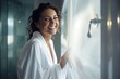 © Bargais - Smiling woman in white silk bathrobe in bathroom.