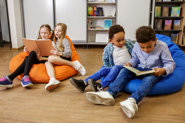 Wall Mural - Children reading book in classroom. Back to school. Beginning of school lesson. break time