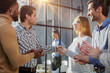 © Katsiaryna - Multiethnic business people shaking hands in office lobby