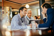 © Marko Geber - Diverse group of businessmen having a meeting in a cafe and discussing business