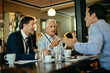 © Marko Geber - Diverse group of businessmen having a meeting in a cafe and discussing business