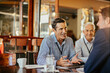 © Marko Geber - Diverse group of businessmen having a meeting in a cafe and discussing business