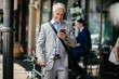 © Marko Geber - Mature businessman using a smart phone while commuting to work with his bicycle