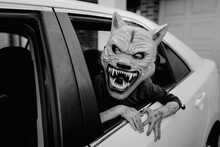 Child Wearing A Halloween Werewolf Mask, Leaning Out Of A Car Window