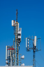 Close-up Of Tower With 6G, 5G, 4G Cellular Network Antenna On Blue Sky Background. Cellular Antenna With Many Power Cables, Coaxial Cables, Optical Fiber.