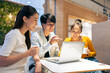 © Kawee - Group of Asian friends talking and using laptop computer in restaurant.