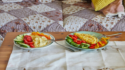 Canvas Print - Morning healthy breakfast of scrambled eggs with parmesan cheese, cucumbers, cherry tomatoes and sweet peppers on the coffee table in front of the sofa