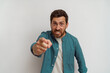 © Daria - Indignant man standing over white background pointing displeased and angry to you on camera