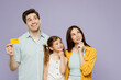 © ViDi Studio - Young parents mom dad with child kid daughter girl 6 year old wear blue yellow casual clothes hold mock up credit bank card look aside on area isolated on plain purple background Family day concept