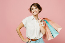 Young Woman Wear Casual Clothes Hold Shopping Paper Package Bags Look Aside Ona Rea Stand Akimbo, Arm On Waist Isolated On Plain Light Pink Color Background Studio. Black Friday Sale Buy Day Concept.