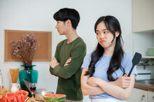 Unhappy And Angry Asian Couple Ignoring Each Other, Arguing While Cooking In The Kitchen Together.