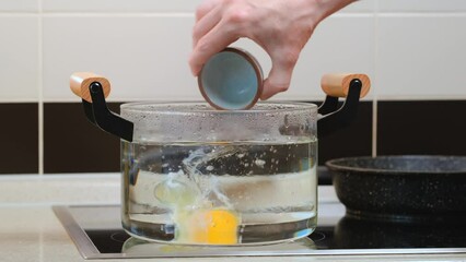 Wall Mural - Poaching an egg in a transparent pot with boiling water