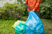 Garbage Sorting By Type In Colored Packages, Recycling Of Environmental Waste. Eco Friendly People Sort Garbage. Yellow Paper, Red Metal, Green Glass, Blue Plastic. 