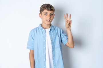 Wall Mural - Beautiful kid boy wearing  casual clothes showing and pointing up with fingers number three while smiling confident and happy.