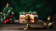 Köstliche, angeschnittene Weihnachtstorte mit Beeren auf goldener Tortenplatte vor festlichem, grünen Weichnachthintergrund mit Christbaumkugeln und Tannenbaum, Weihnachtsessen
