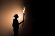 © Bonsales - Silhouette of torchbearer athlete standing with Olympic torch at sunset with copyspace on black background