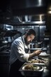 © OMD - shot of a chef using his phone while working in the kitchen at a restaurant