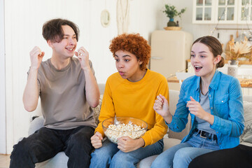 Wall Mural - Group of friends watching sport match soccer football game on tv. Happy football fans celebrating victory at home. Friendship sports entertainment concept. Diverse buddies having fun together at home