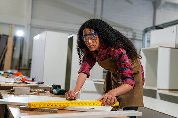 Wall Mural - Young woman working as carpenter in a small carpentry workshop, Small family business concept of young entrepreneurs