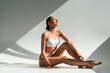 © standret - In the sunlight. Young woman with slim body type is in fitness clothes in the studio