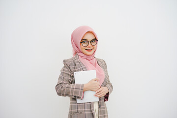 Wall Mural - Portrait of a happy beautiful young muslim businesswoman pink hijab, company worker in glasses, smiling and holding digital tablet, standing over white background.