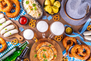 Wall Mural -  Oktoberfest munich traditional festival menu foods - bavarian sausages, pretzels, potato, sauerkraut, beer bottle and mug,  Background flyer for Oktoberfest invitation on old wooden table