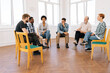 Remote view of diverse support group during meeting with professional senior male therapist. Multi-ethnic men and women looking serious during team counselling session. Concept of mental health